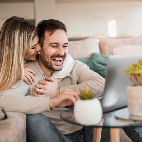 Young couple relaxing on sofa with laptop.Love,happiness,people and fun concept.