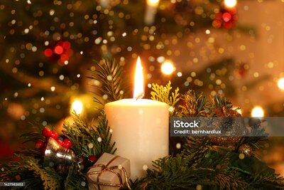 burning advent candle Christmas decoration with flare lights in front of a Christmas tree