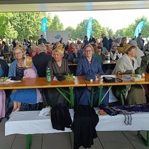 einige Goldhaubenfrauen beim Juniafest sitzend auf Bierbänken